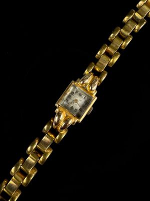 a close up of a watch on a black surface with a black background