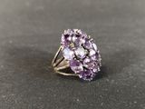 a close up of a ring with purple stones on a black surface