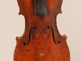 an old violin hanging from a string on a white wall