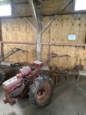 un tracteur garé dans une grange, avec une charrue attelée