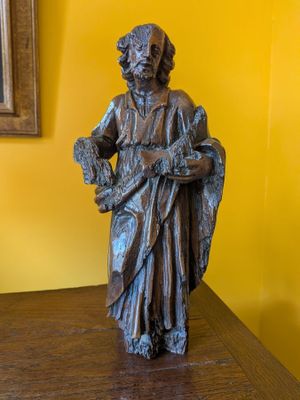 statue d'un homme tenant un panier de fleurs posé sur une table en bois