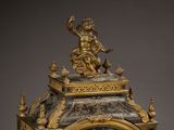 a gold clock with a statue on top of it