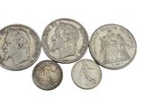 a group of silver coins sitting on top of a white surface