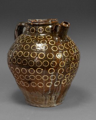 a brown vase with circles on it sitting on a table