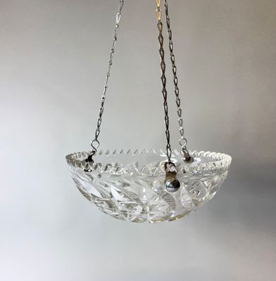 un bol en verre suspendu à une chaîne fixée au mur