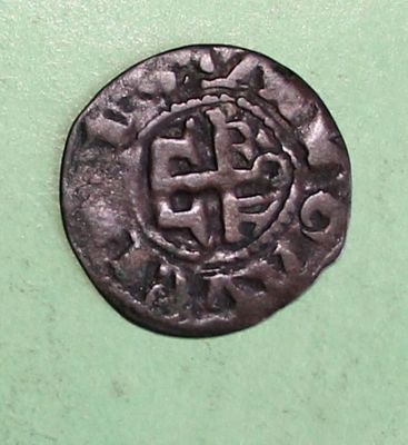 an old coin with a cross on it sitting on a green surface