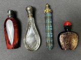 trois flacons de parfum en verre, aux motifs et couleurs variés, posés sur un fond gris
