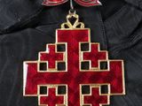 a close up of a red and gold cross with a bow