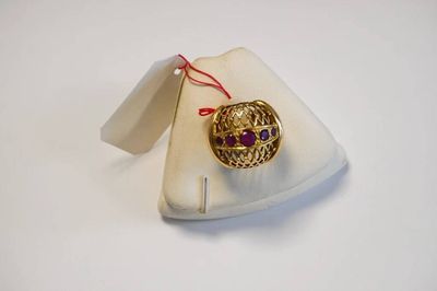 une photo d'une bague en or sertie de pierres violettes, posée sur une assiette blanche