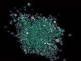 some pieces of green glass are scattered on a black surface