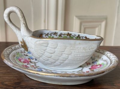 a white bowl and saucer with a spoon on a wooden table