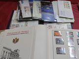 beaucoup de timbres posés sur une table, avec une boîte remplie de timbres à côté