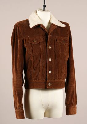 La veste est marron et blanche, avec un col en fourrure.