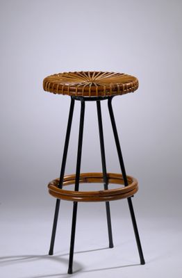une photo d'un tabouret en osier avec des pieds noirs et une assise en bois