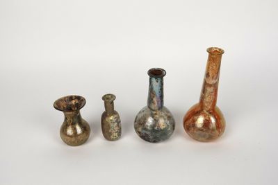 four different colored glass vases sitting next to each other on a white surface
