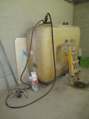 un grand réservoir jaune posé dans un garage, à côté d'une échelle