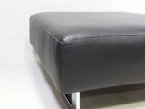 a black leather ottoman sitting on a white surface