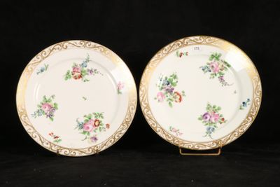 two plates with floral designs on them are sitting on a black surface