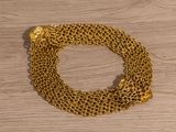 a close up of a gold chain bracelet on a wooden surface