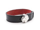 un bracelet en cuir noir muni d'un fermoir en argent, sur fond blanc