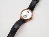 gros plan d'une montre sur une surface blanche avec un bracelet noir