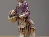 a figurine of a man holding a basket of flowers