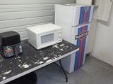 deux micro-ondes posés sur une table à côté d'un réfrigérateur