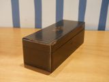 a black box on a wooden table with a striped wall behind it