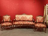 four chairs and a couch in a room with a red wall
