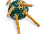 a green and yellow toy with four wooden legs on a white surface