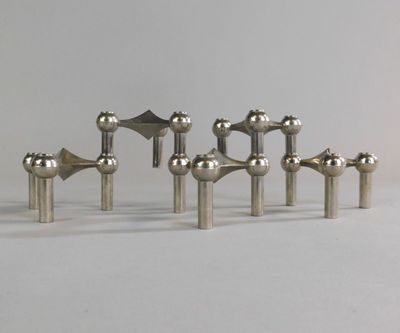 six objets métalliques argentés sont disposés en rangée sur une surface blanche