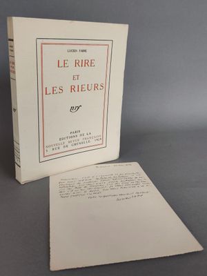 Le livre est ouvert et posé sur la table, à côté d'une feuille de papier.