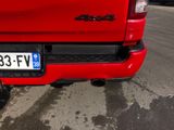 a red truck parked in a parking lot with a license plate on the back