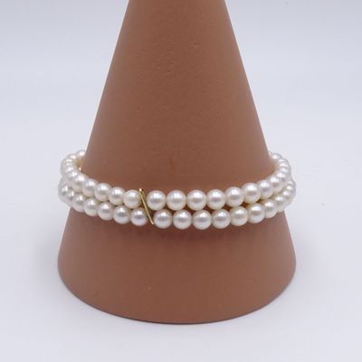 bracelet de perles avec un fermoir doré sur un cône à fond blanc
