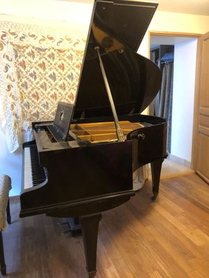 un piano noir posé dans un salon, à côté d'un fauteuil