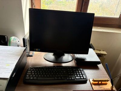 un écran d'ordinateur et un clavier posés sur un bureau devant une fenêtre