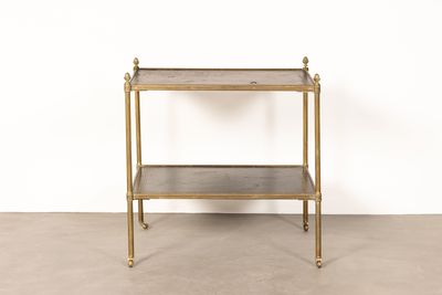 une table en métal doré surmontée d'une étagère en verre