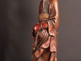 an old wooden statue of a man with a hat and robe