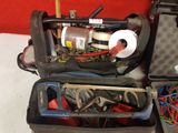two open suitcases with tools in them on a table