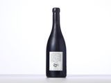 a bottle of wine sitting on top of a table next to a white wall