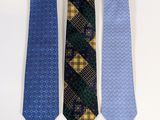 three ties are lined up on a white surface, one is blue and the other is yellow