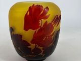a yellow and red vase with a red flower on it
