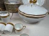 a lot of white and gold dishes and cups on the table