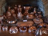 many different types of copper pots and pans on the table