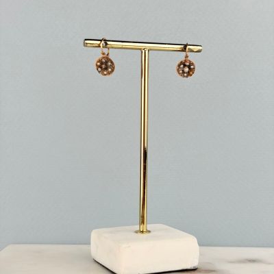 une paire de boucles d'oreilles posée sur un présentoir, sur une surface en marbre