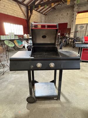 une photo d'un barbecue dans un garage, avec une table et des chaises