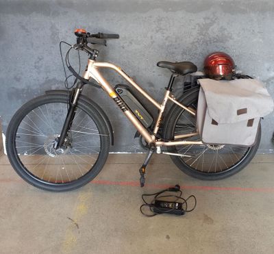 un vélo garé contre un mur, avec un sac posé dessus