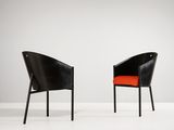 deux chaises noires avec des coussins orange dans une pièce blanche