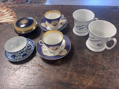 plusieurs tasses et soucoupes posées sur une table, avec un ventilateur en arrière-plan