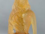 yellow jade statue of a woman holding a bird on a rock
